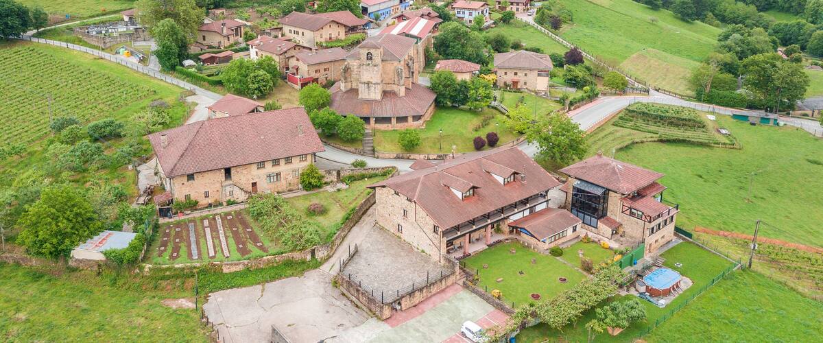 A rural village with stone buildings, terraced fields, and a church.