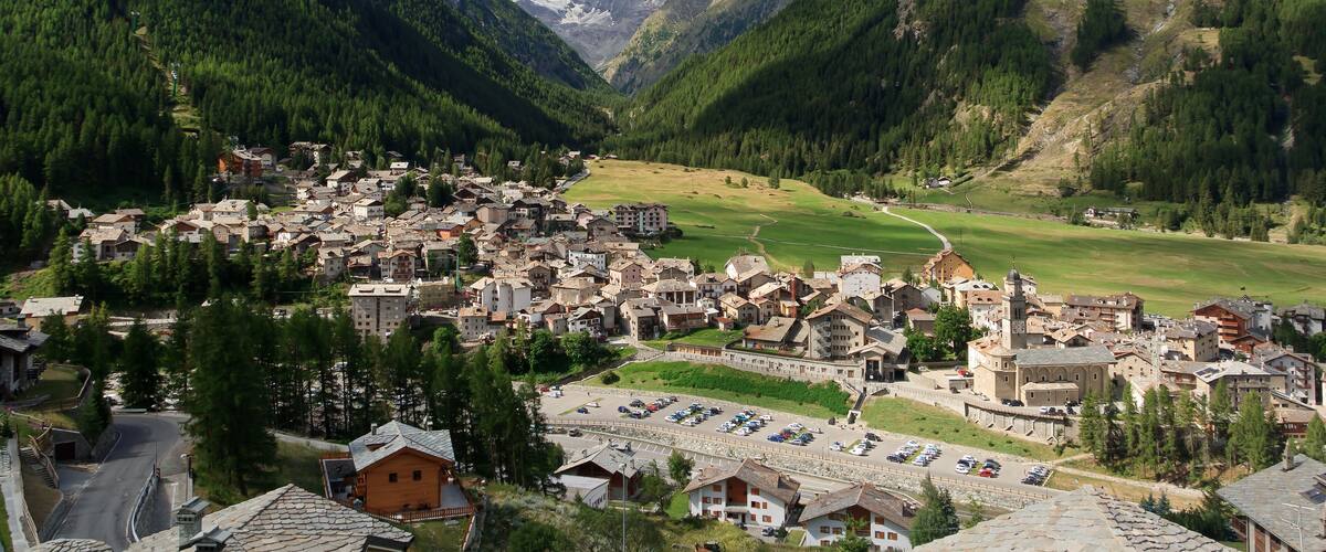 A mountainous town with a central church, surrounded by lush forests and a valley.