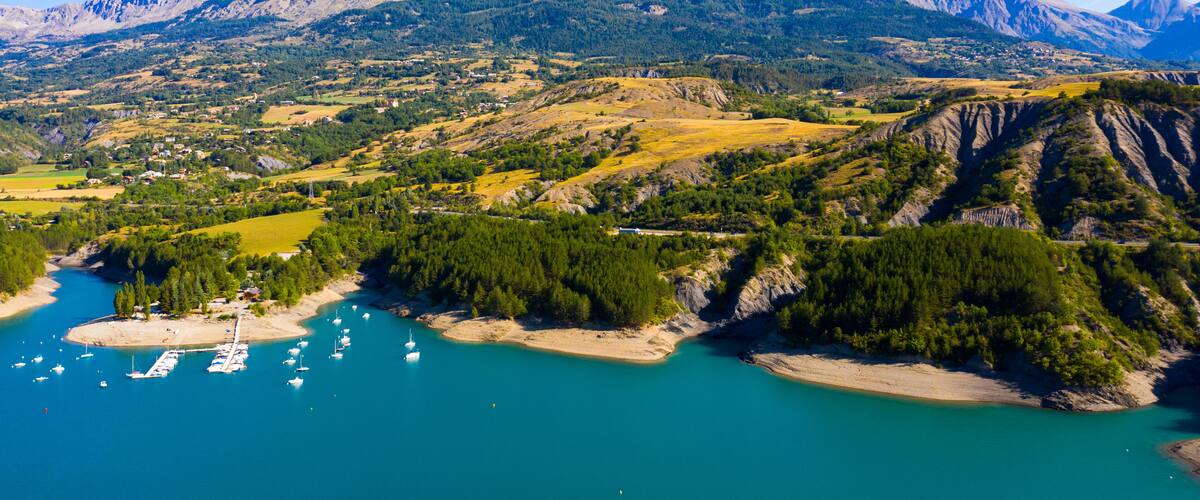 A coastal landscape with mountains, a marina, and a river.