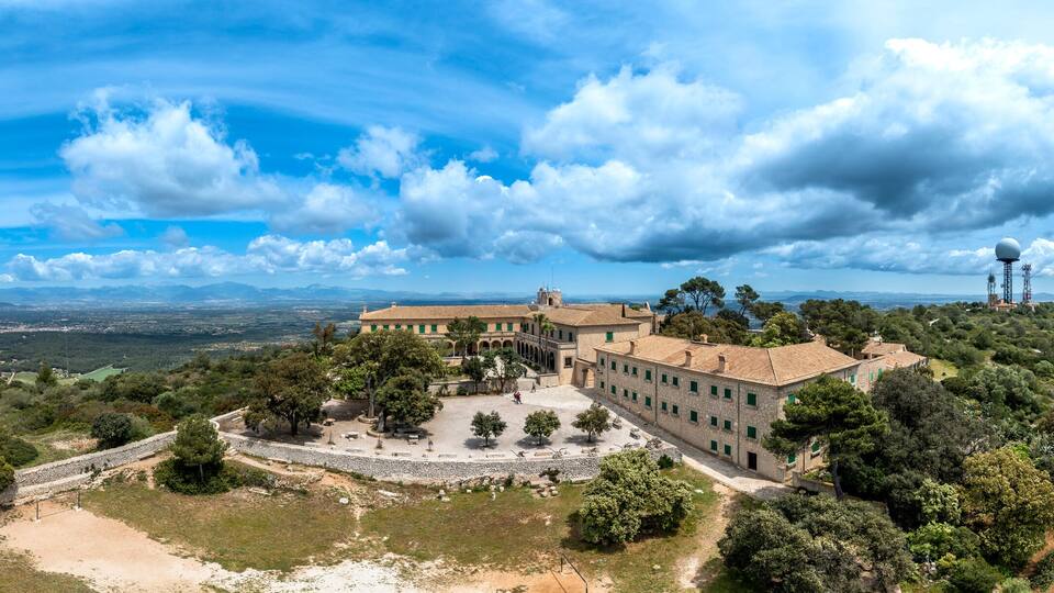 A historic building surrounded by trees and hills.