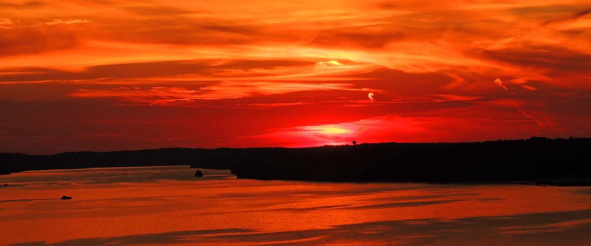 A sunset over a body of water with a red sky.