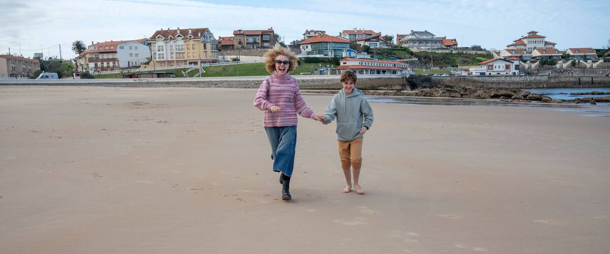 A sandy beach with houses in the background.