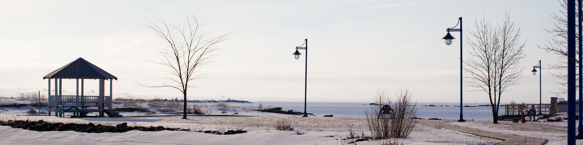 Wood path walkway to pavilion at frozen lake shore on a calm winter morning