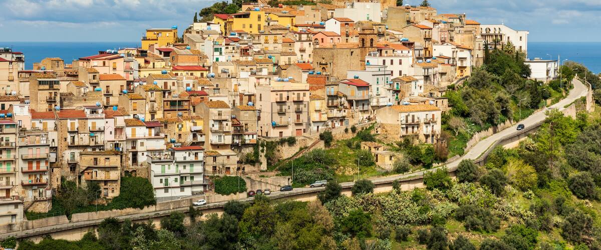 A densely packed hillside town with historic buildings and a prominent castle on top.