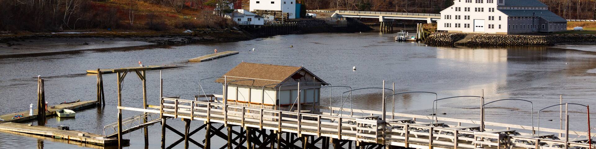 A river with a wooden pier and a white building on stilts.