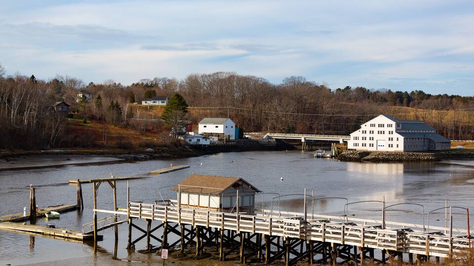 A river with a wooden pier and a white building on stilts.