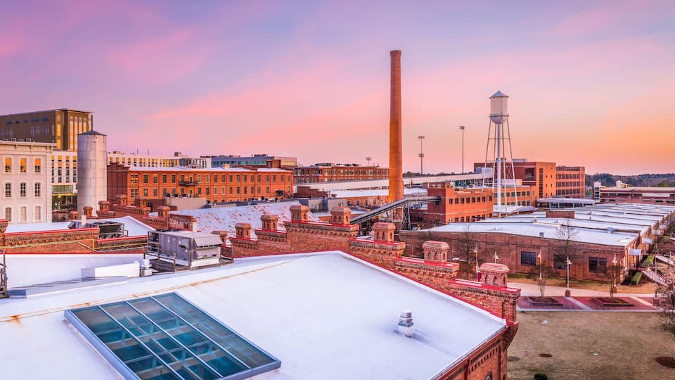 A cityscape with industrial buildings, a tall chimney, and a water tower.