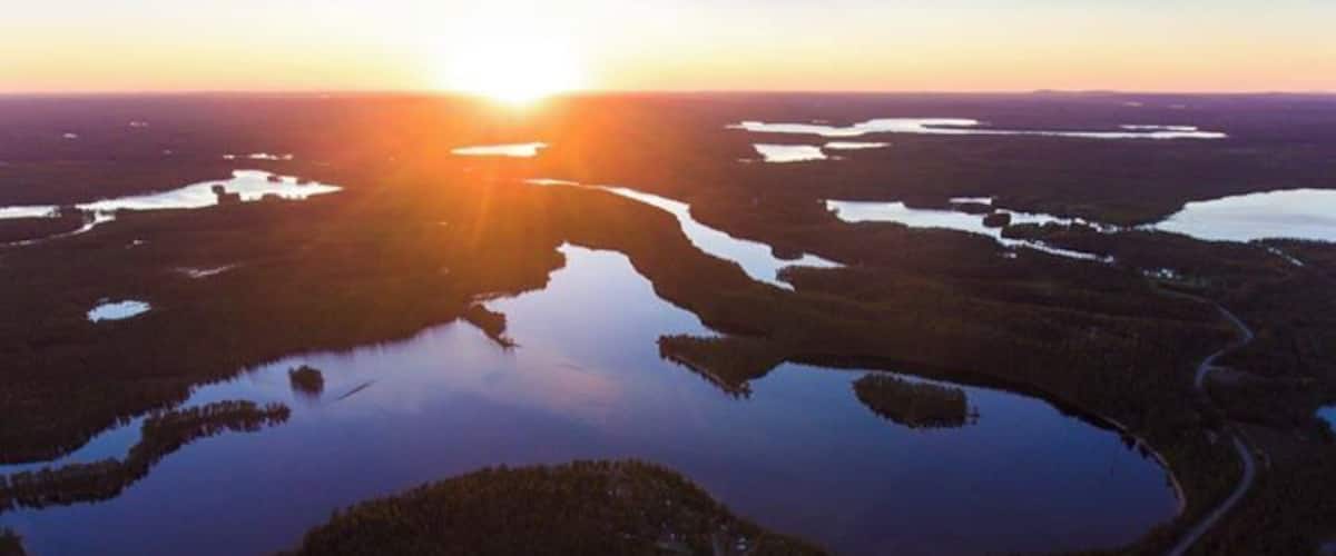A sunset over a network of lakes surrounded by dense forests.