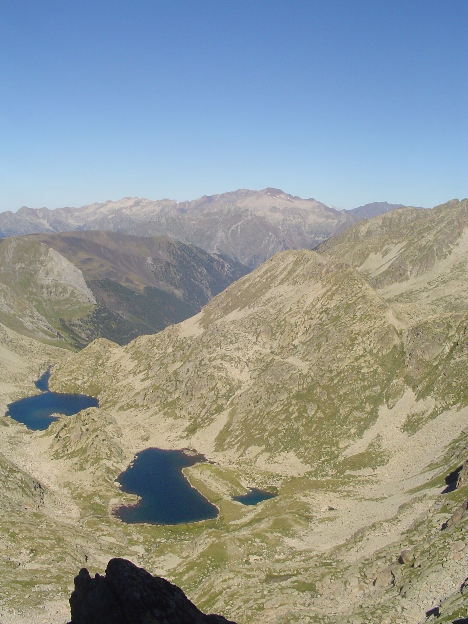 A mountainous landscape with two lakes and distant snow-capped peaks.