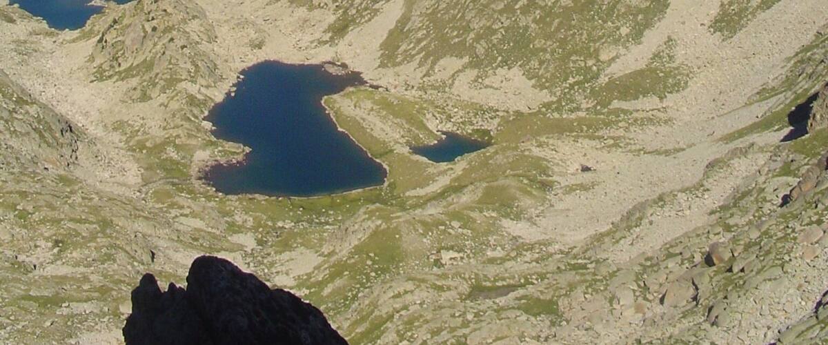 A mountainous landscape with two lakes and distant snow-capped peaks.