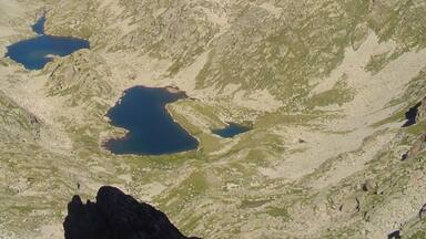 A mountainous landscape with two lakes and distant snow-capped peaks.