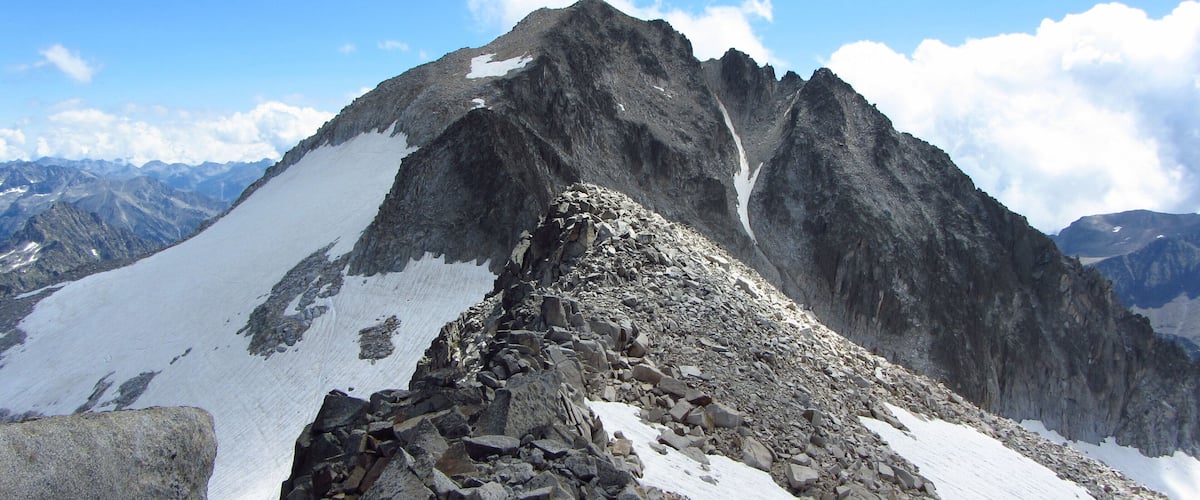 A rugged mountain peak with snow patches and rocky terrain.