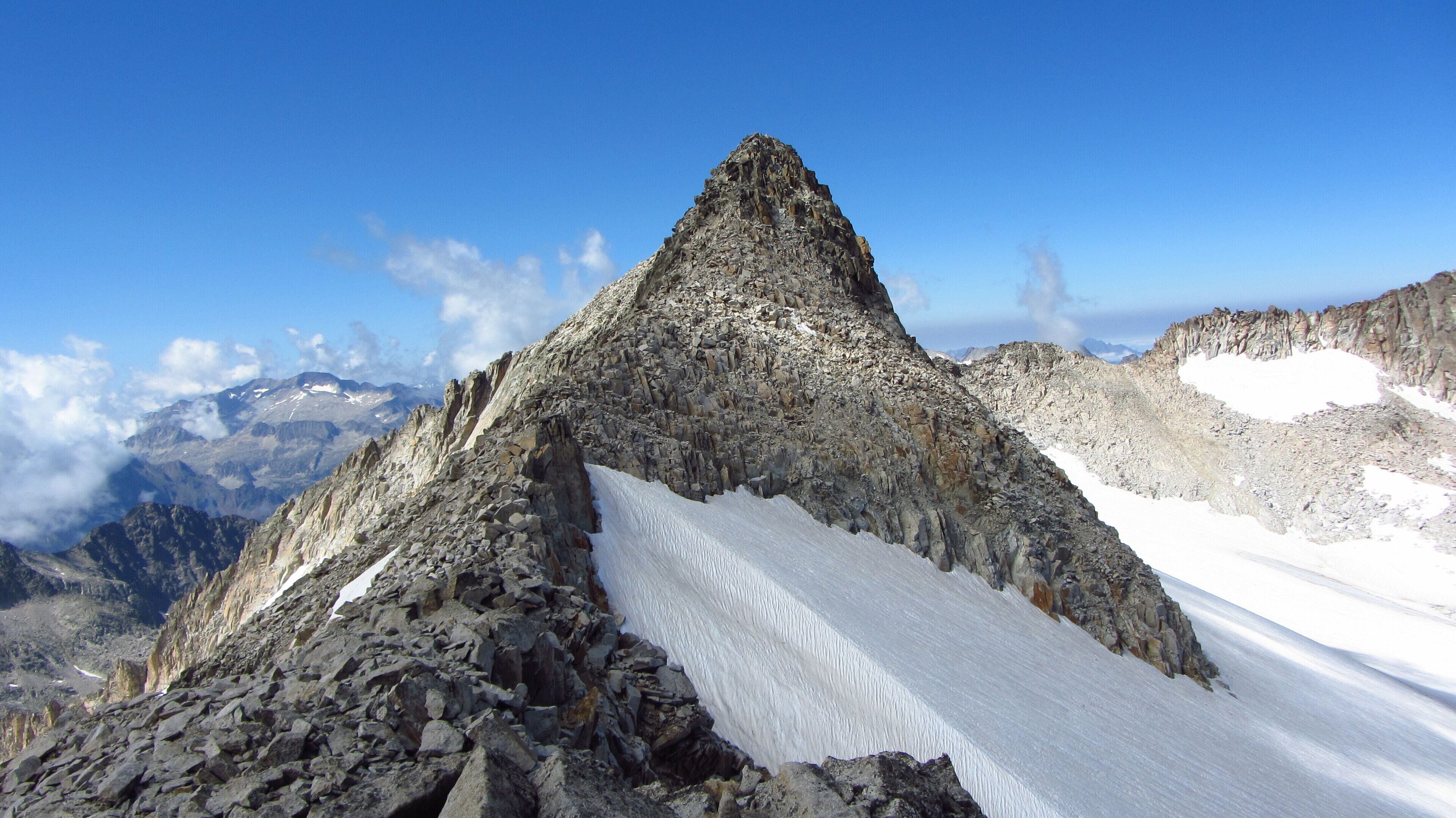 A rugged mountain peak with a snow-covered slope and rocky terrain.