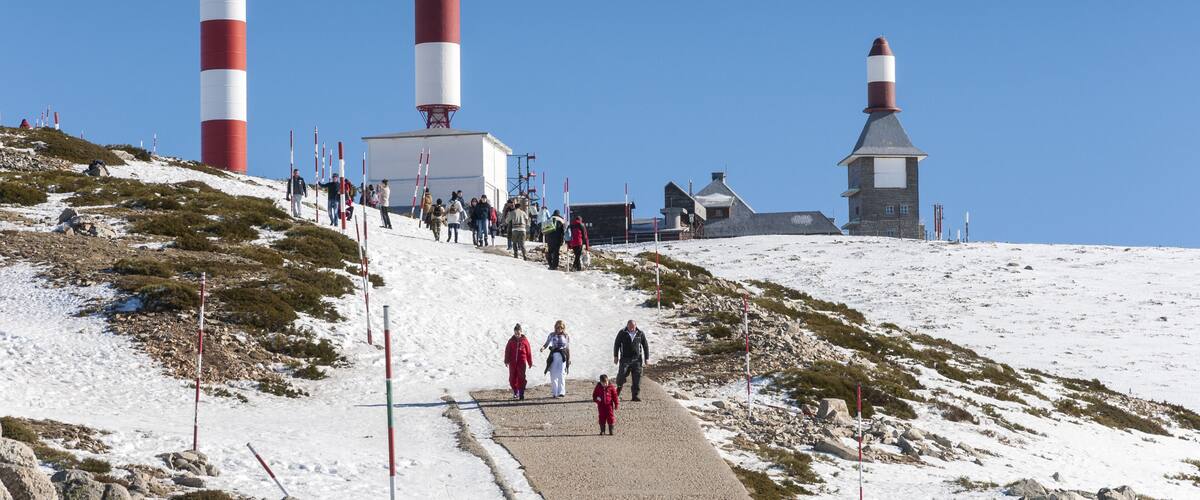 A snowy landscape with three lighthouses and a path with people walking.
