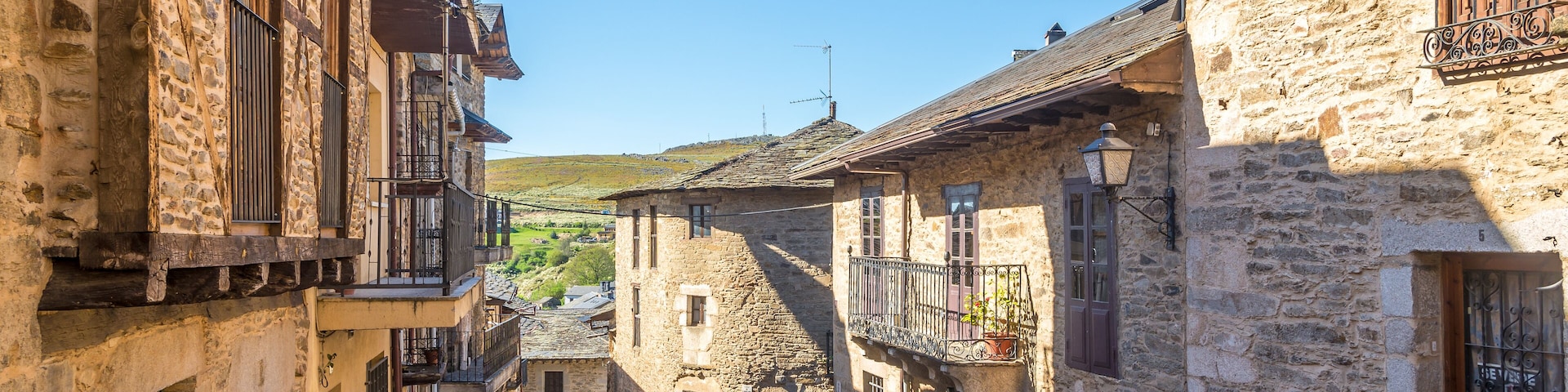 A narrow cobblestone street flanked by stone buildings with wooden shutters and balconies.