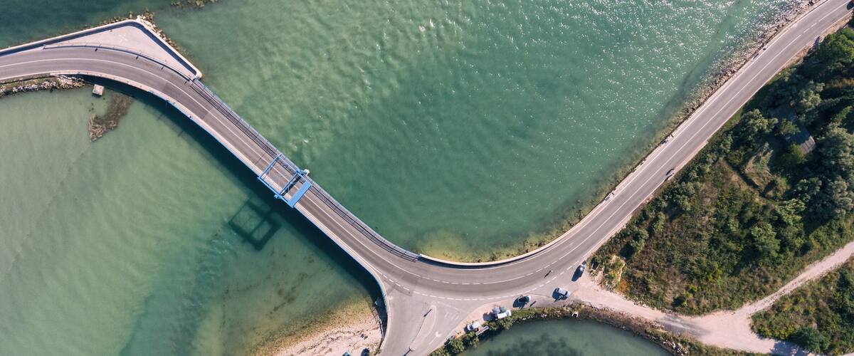 An aerial view of a bridge connecting two landmasses over a body of water.