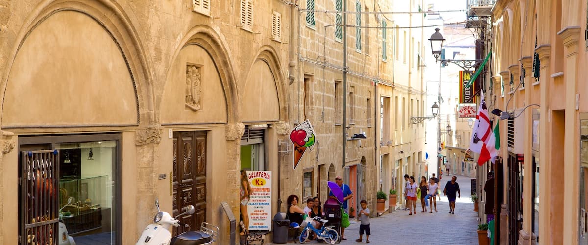 A narrow cobblestone street lined with historic buildings, a parked scooter, and people walking.