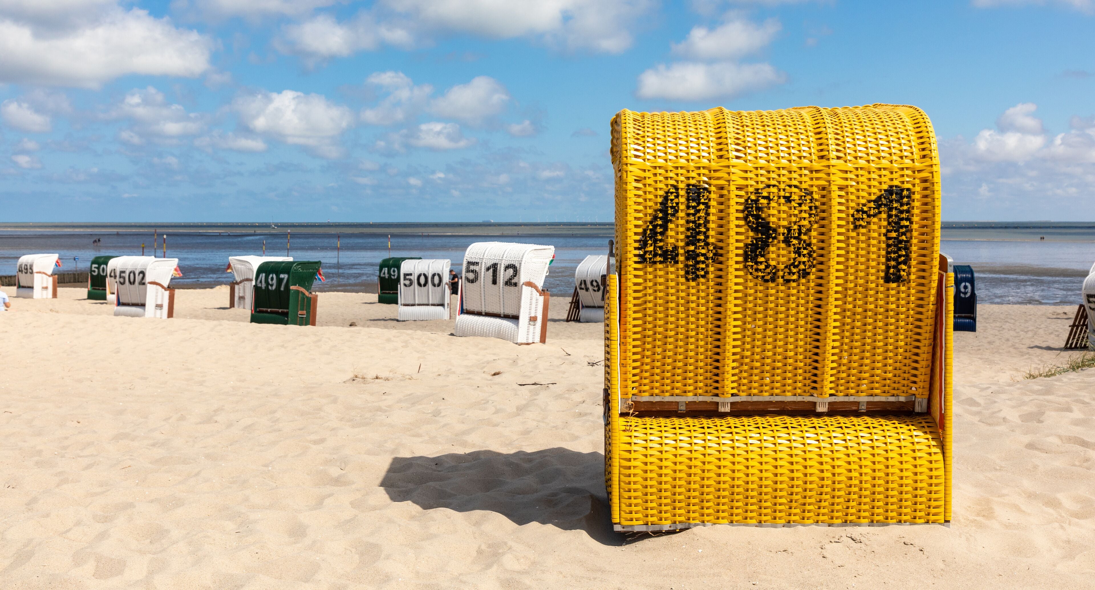 A beach with numbered beach chairs and a large yellow chair labeled 481.
