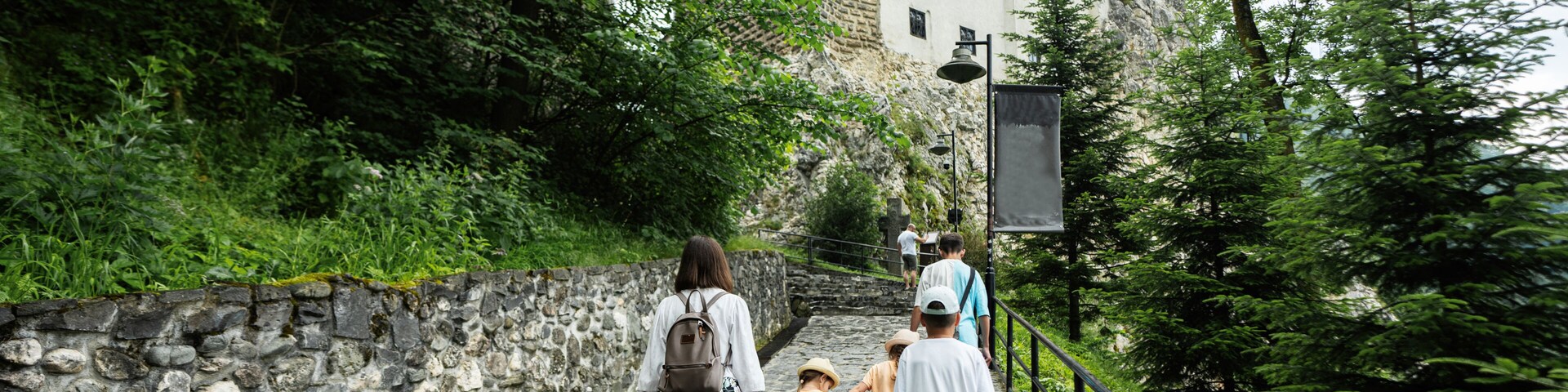 Un sendero de piedra que lleva a un castillo rodeado de abundante vegetación.