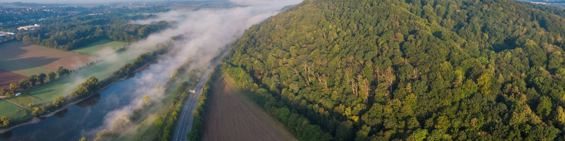 A lush green hill with a church on top, a river flowing through a valley, and a clear sky.
