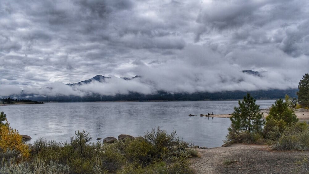 A lake with mountains in the background, surrounded by vegetation.