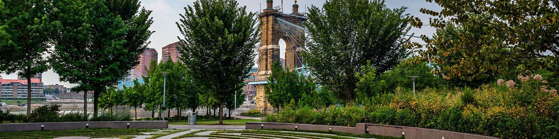 Un jardín ajardinado con un laberinto, árboles y una torre a lo lejos.