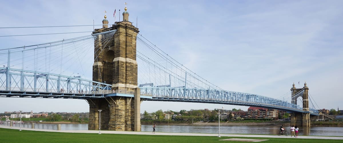 A large suspension bridge with a stone tower and a smaller tower on the right.