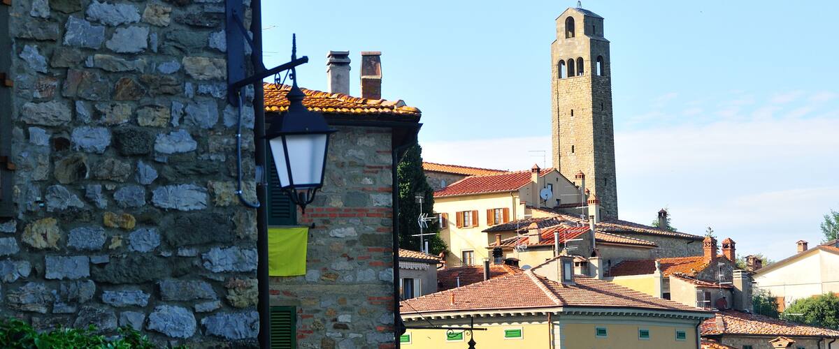 A stone building with a clock, a bell tower, and a street lamp.