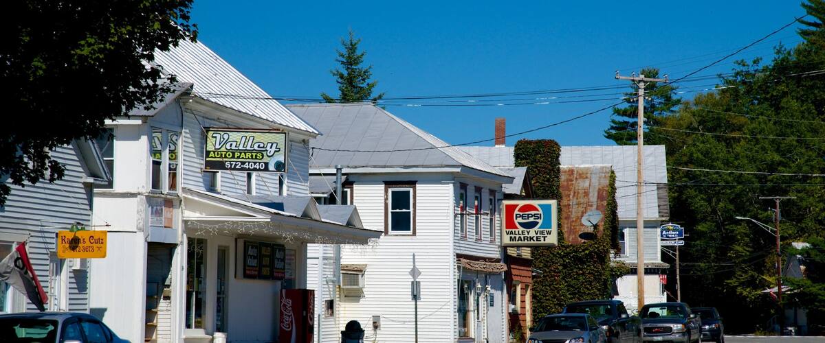 A street with white buildings, a car dealership, and a market.