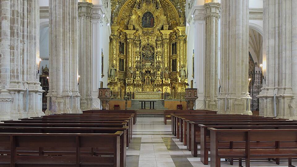An ornate church interior with rows of wooden pews and a central altar.