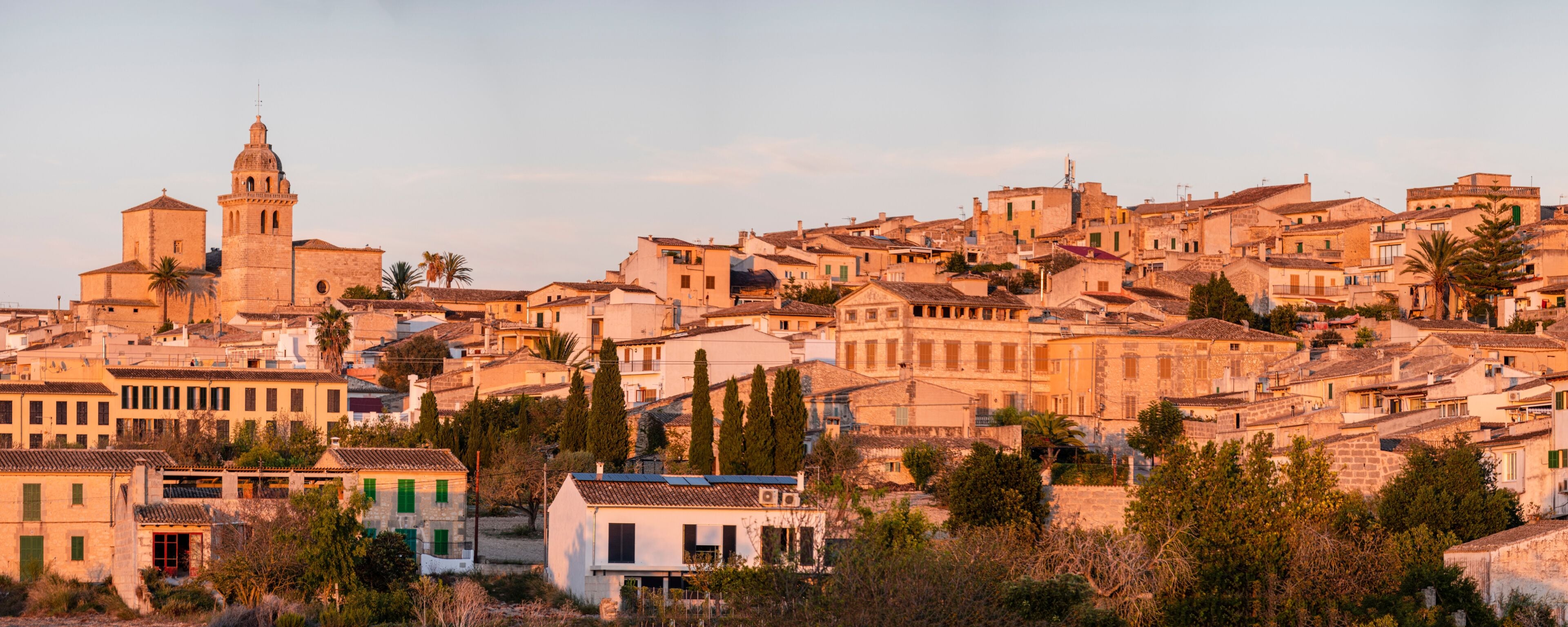 A historic town with a prominent church tower, dense residential buildings, and lush greenery.