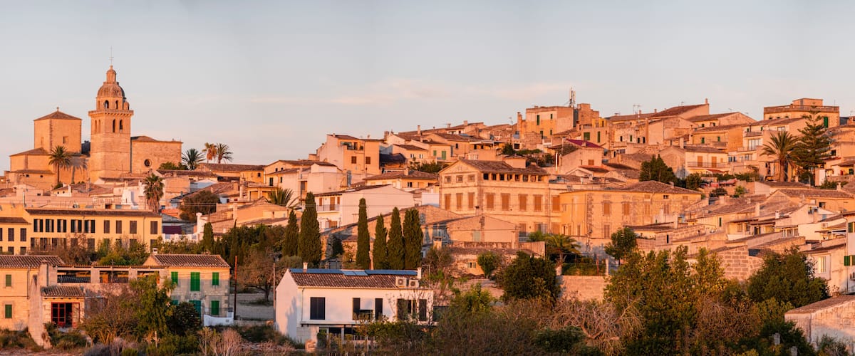 A historic town with a prominent church tower, dense residential buildings, and lush greenery.