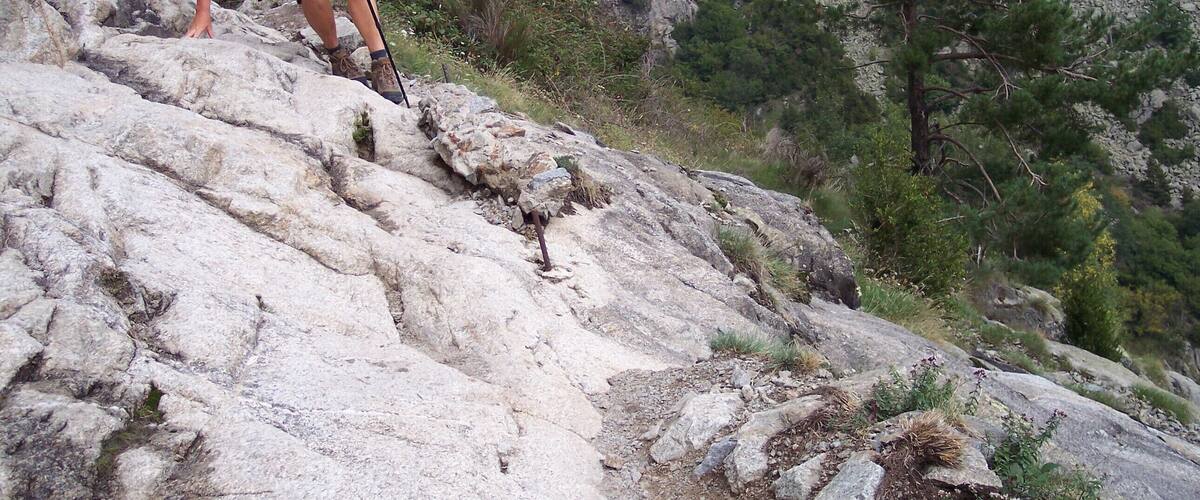 A hiker climbing a rocky mountain path.