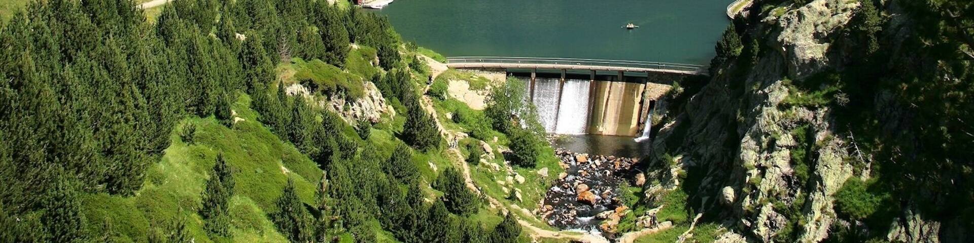 A mountainous landscape with a lake, a bridge, and a building complex.