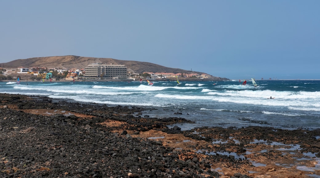 Summer views of the eastern coast of the town towards Montana Pelada with surfers practicing water sports such as surfing and windsurfing, El Medano, Tenerife, Canary Islands, Spain