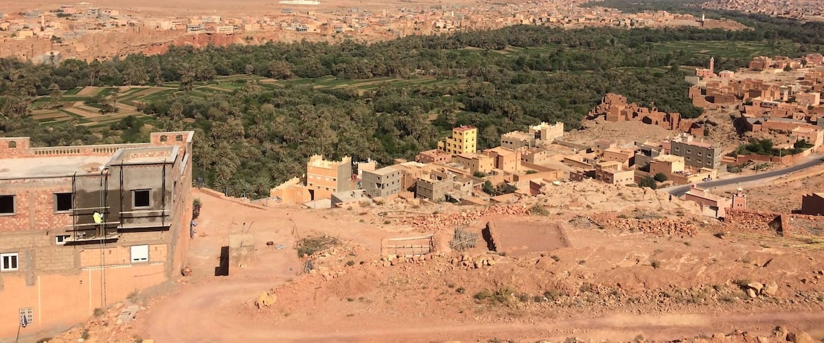 A desert landscape with a town in the foreground and a mountain range in the distance.