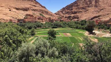 Un pueblo enclavado en un valle con campos en terrazas y edificios de tejados rojos.