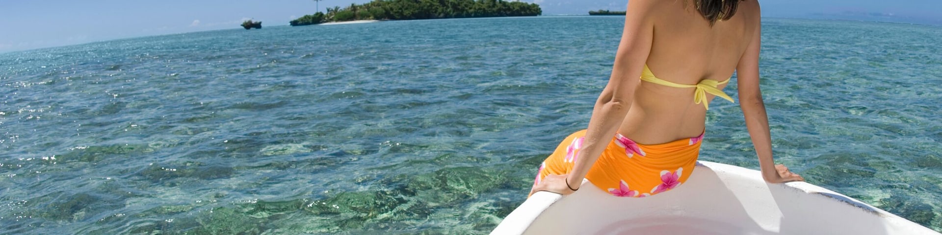 Fiji, Vanua Levu Island, woman sitting on bow of boat, rear view