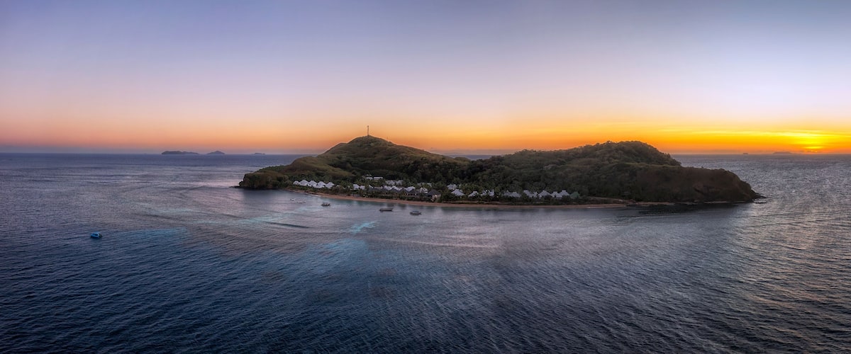 A tropical island with a small settlement at sunset.