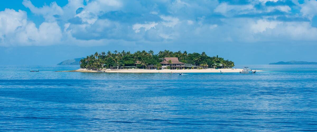 A tropical island with palm trees, a beach, and a clear blue sky.