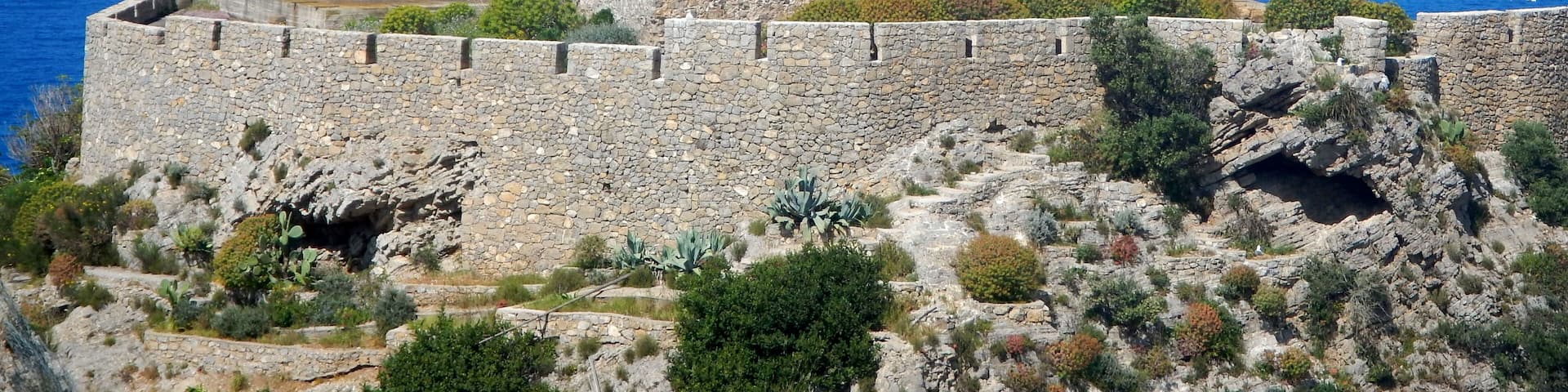 A stone tower with a crenellated top, overlooking a coastal landscape.