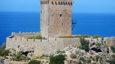 A stone tower with a crenellated top, overlooking a coastal landscape.