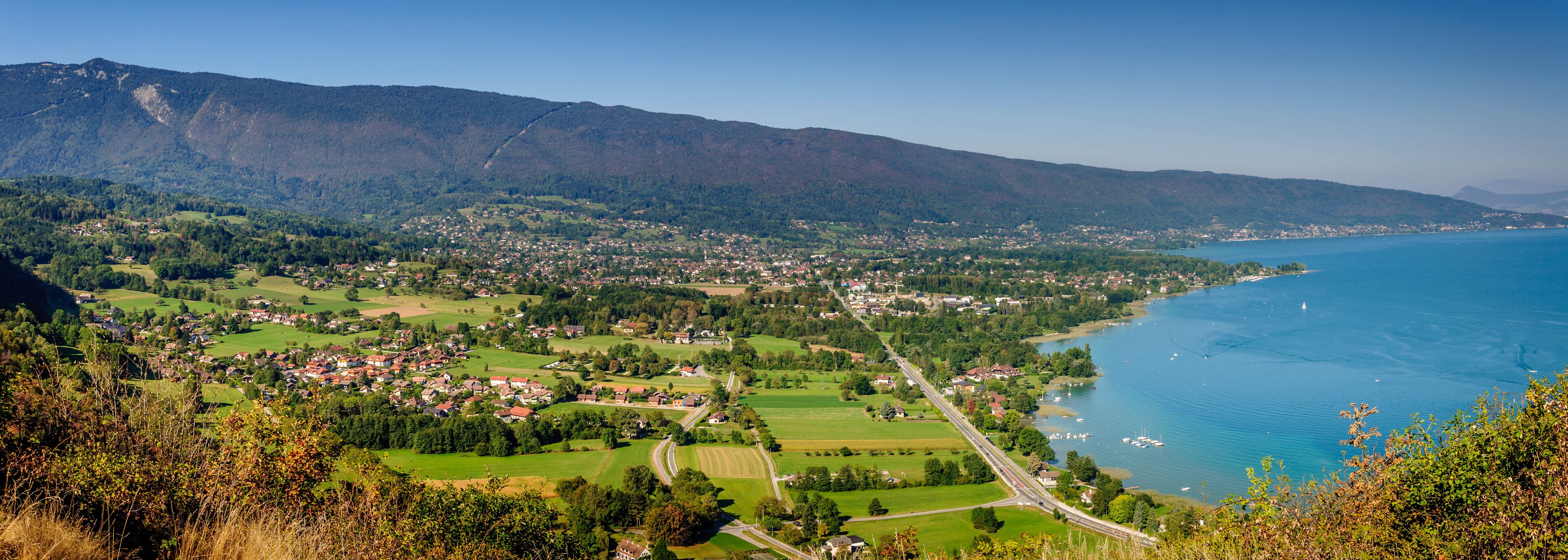 A coastal town with a mountain backdrop, a winding road, and a lake.