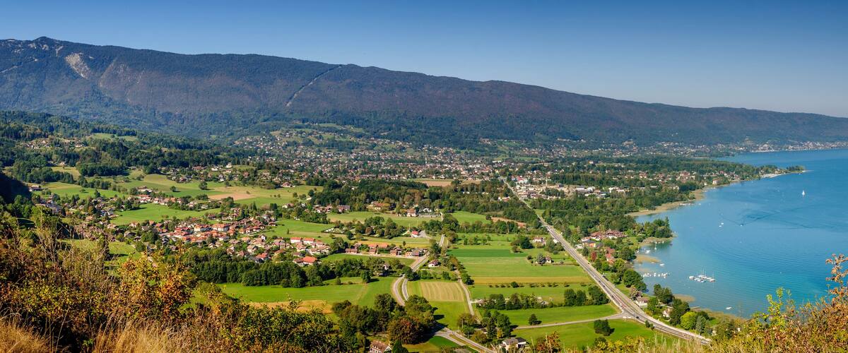 A coastal town with a mountain backdrop, a winding road, and a lake.