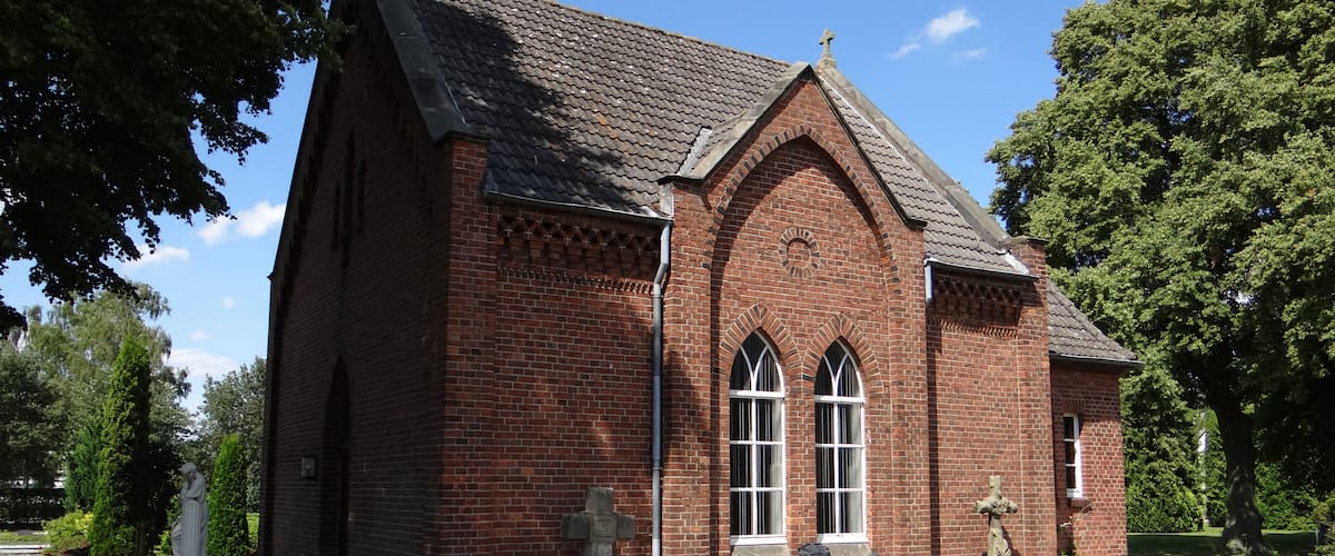A red brick church with a steep roof and arched windows.