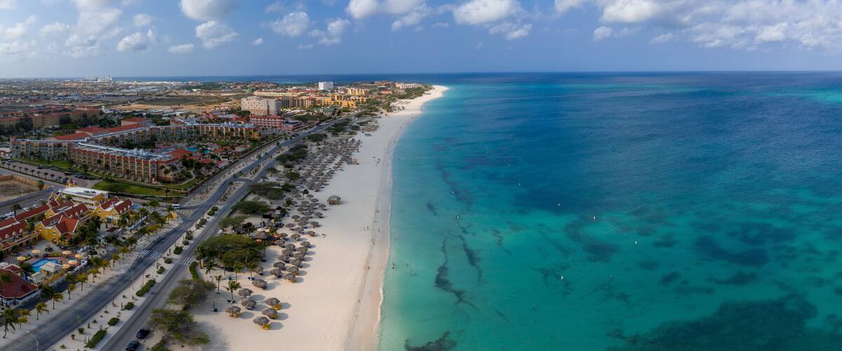 A coastal city with a long sandy beach, clear turquoise waters, and a mix of urban and resort buildings.