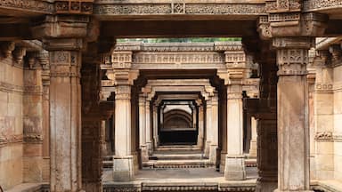An intricately carved stone corridor with multiple arches and columns, leading to a dark interior.