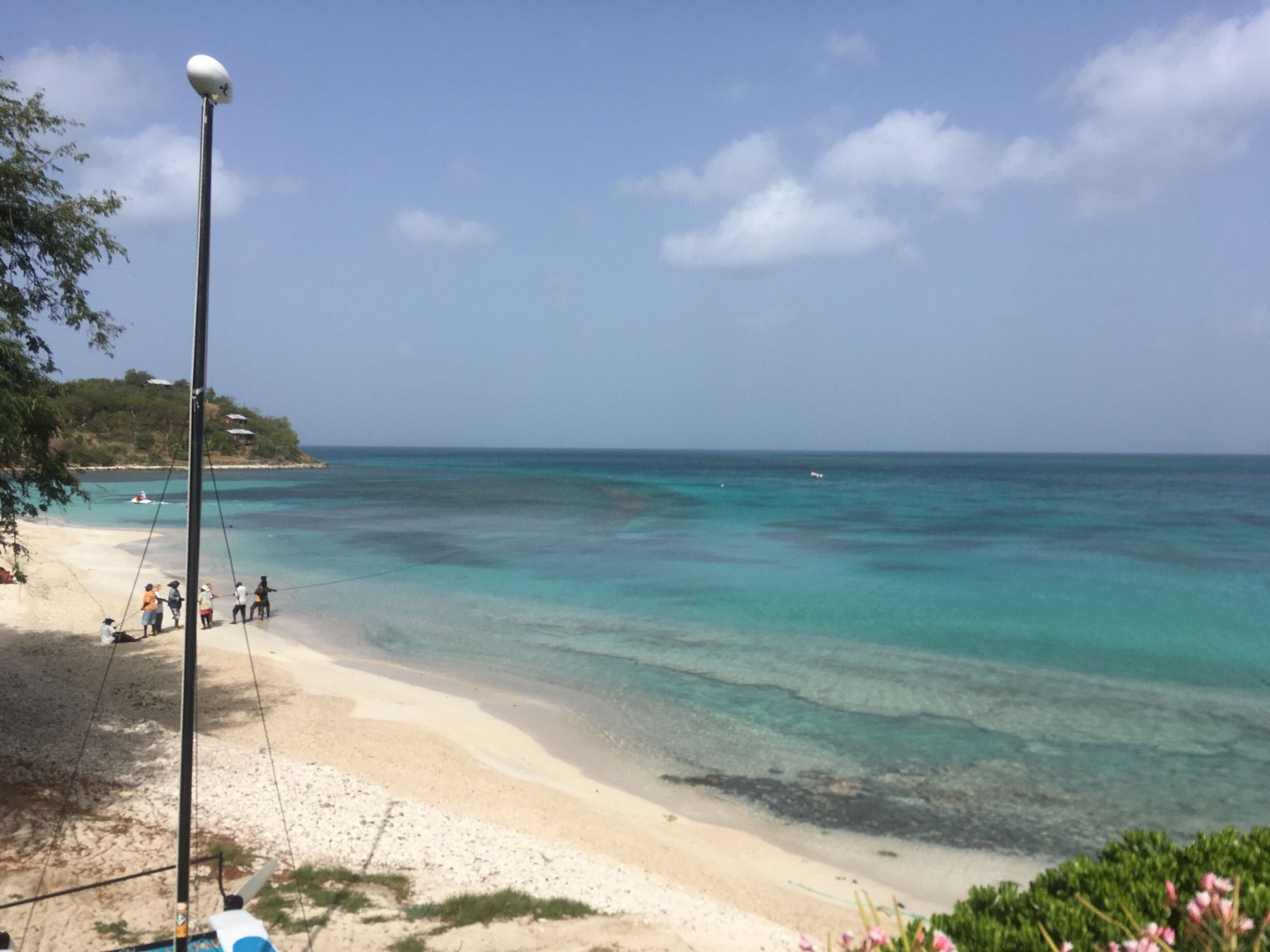One of 2 adjacent beaches called Ffryes beach in Antigua West Indies. The dark patches you can see are reefs in shallow water. Really warm and lovely water to swim and snorkel in. In this picture you also see local fisherfolk pulling in their nets for their morning catch. Very traditional way of fishing with simple nets