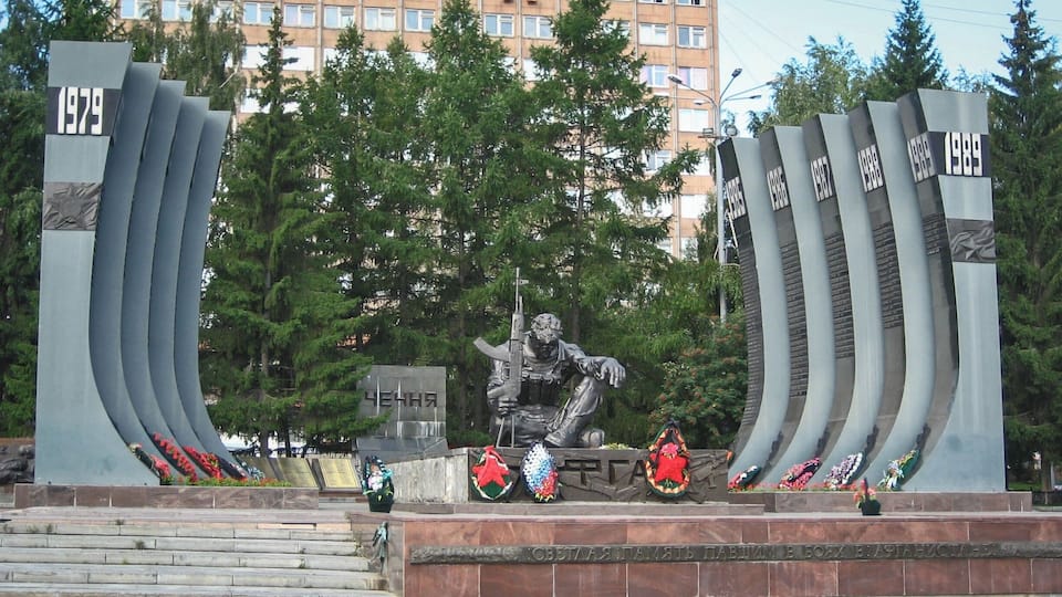 Located in Ekaterinburg is the Yekaterinburg War Memorial, better known as the Black Tulip War Memorial.
In the center of the memorial sits a soldier. He has his rifle in one hand, and his other arm rests over a raised knee. The soldier has his head bowed and he is staring intently at the ground. Etched upon his face is the emotion of complete powerlessness, horror, defeat and devastation.
This strong soldier tears at your heart and evokes emotions of terror and tragedy, for lives that were taken, maimed and lost in both Afghanistan and Chechnya. The soldier was erected in 1996 after the Afghanistan and First Chechen War, and the curved black pillars that flank him, are arranged in date order, and bare the names of the soldiers lost in Afghanistan and Chechnya.
The Yekaterinburg War Memorial, or Black Tulip War Memorial, stands as reminder to all those that visit Ekaterinburg, of the unnecessary loss of life and environmental damage that is suffered at the hands of war.