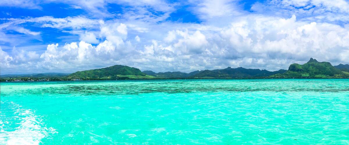 A turquoise sea with a mountain range in the background.